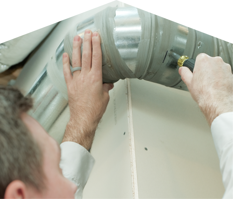 Dunn HVAC technician inspecting and tightening a joint on a sealed metal air duct, performing maintenance work during an air duct cleaning task. Dunn HVAC technician inspecting and tightening a joint on a sealed metal air duct, performing maintenance work during an air duct cleaning task.
