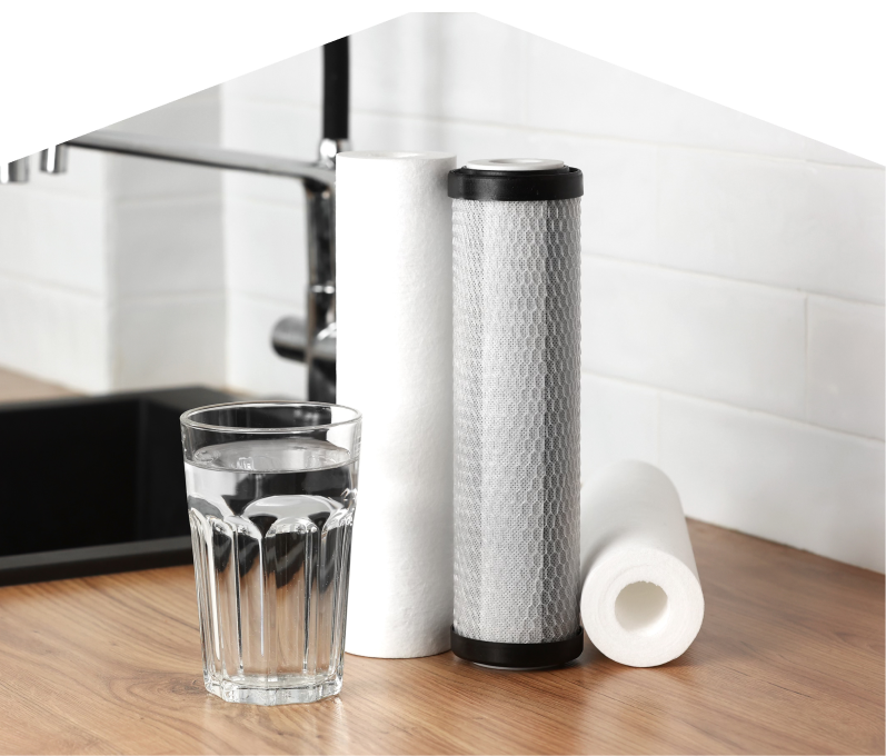 Set of Dunn water filtration cartridges placed beside a clear glass of water on a kitchen countertop, with a sink and modern faucet in the background. Set of Dunn water filtration cartridges placed beside a clear glass of water on a kitchen countertop, with a sink and modern faucet in the background.
