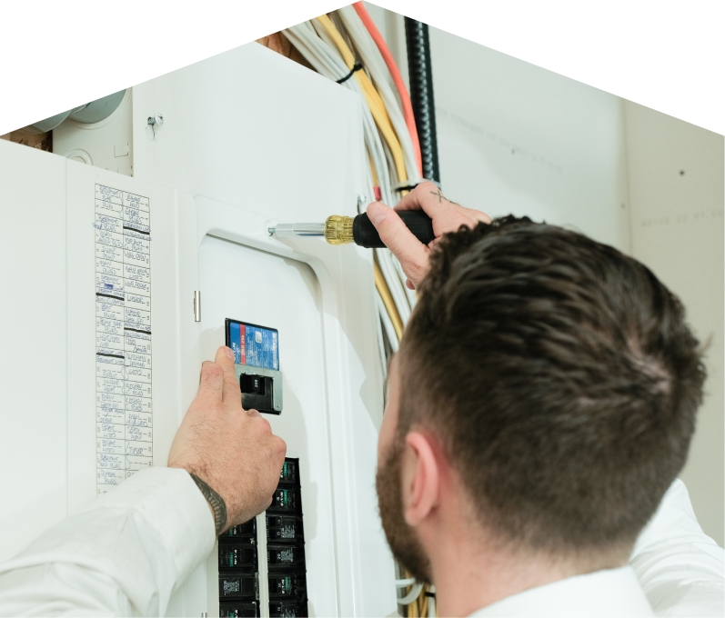 Dunn electrician using a screwdriver to perform an electrical panel upgrade, working near organized wiring in a residential wall. Dunn electrician using a screwdriver to perform an electrical panel upgrade, working near organized wiring in a residential wall.