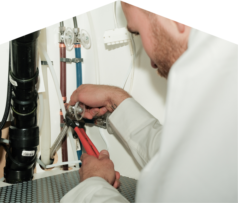 Dunn plumbing expert tightening connections under a sink during a faucet installation, surrounded by hot and cold water supply lines and PVC drainage. Dunn plumbing expert tightening connections under a sink during a faucet installation, surrounded by hot and cold water supply lines and PVC drainage.