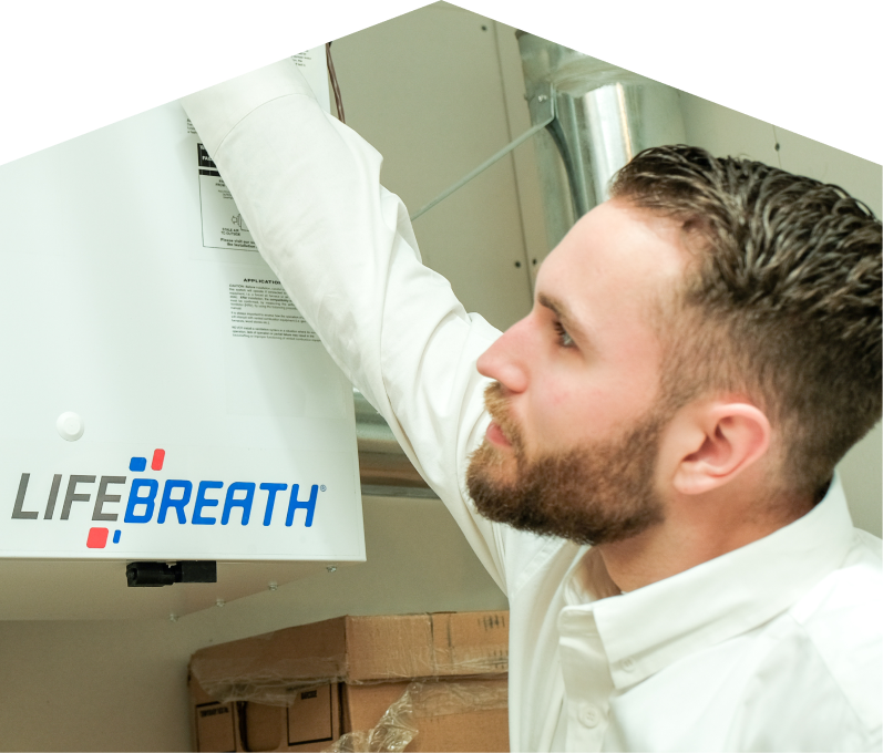 Dunn indoor air quality specialist inspects a Lifebreath ventilation unit related to UV air purifiers, with ductwork and boxes in the background. Dunn indoor air quality specialist inspects a Lifebreath ventilation unit related to UV air purifiers, with ductwork and boxes in the background.