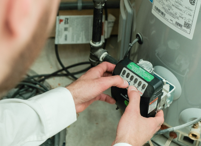 A Dunn technician adjusts the control module on a residential water heater, verifying proper operating settings. A Dunn technician adjusts the control module on a residential water heater, verifying proper operating settings.